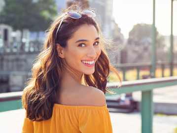 Girl wearing orange staples shirt looking over her shoulder smiling 