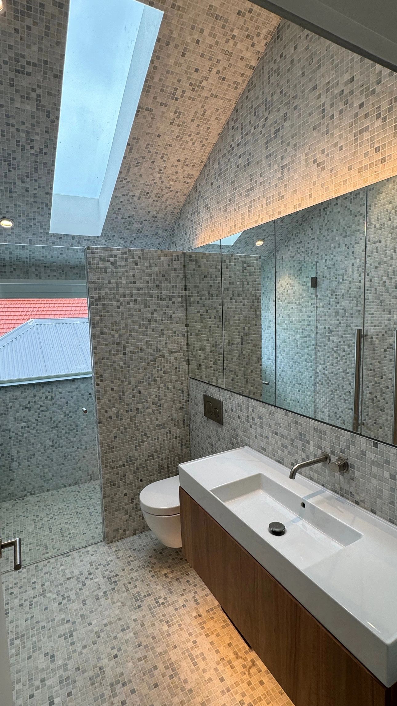 Modern bathroom with mosaic tiles and skylight.
