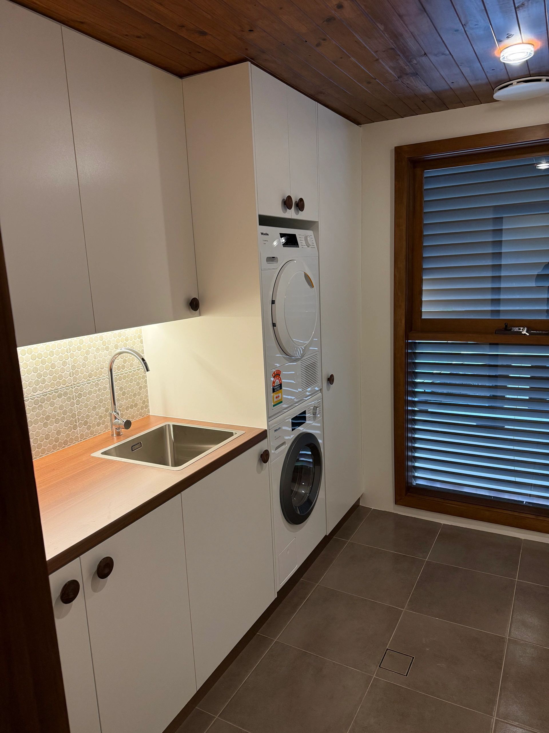 Modern laundry room with washer, dryer, and sink.
