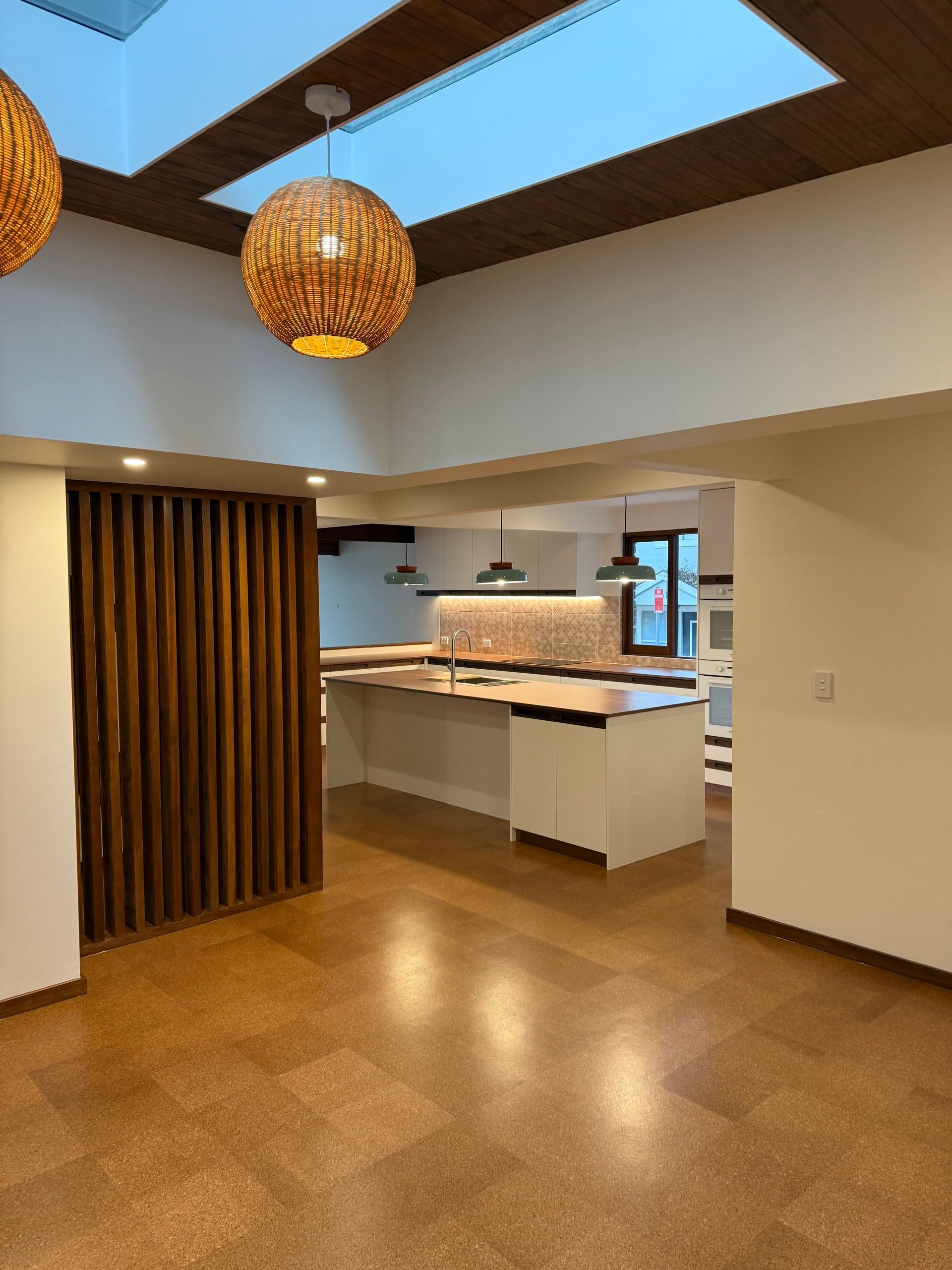 Modern kitchen with wooden accents and pendant lights.