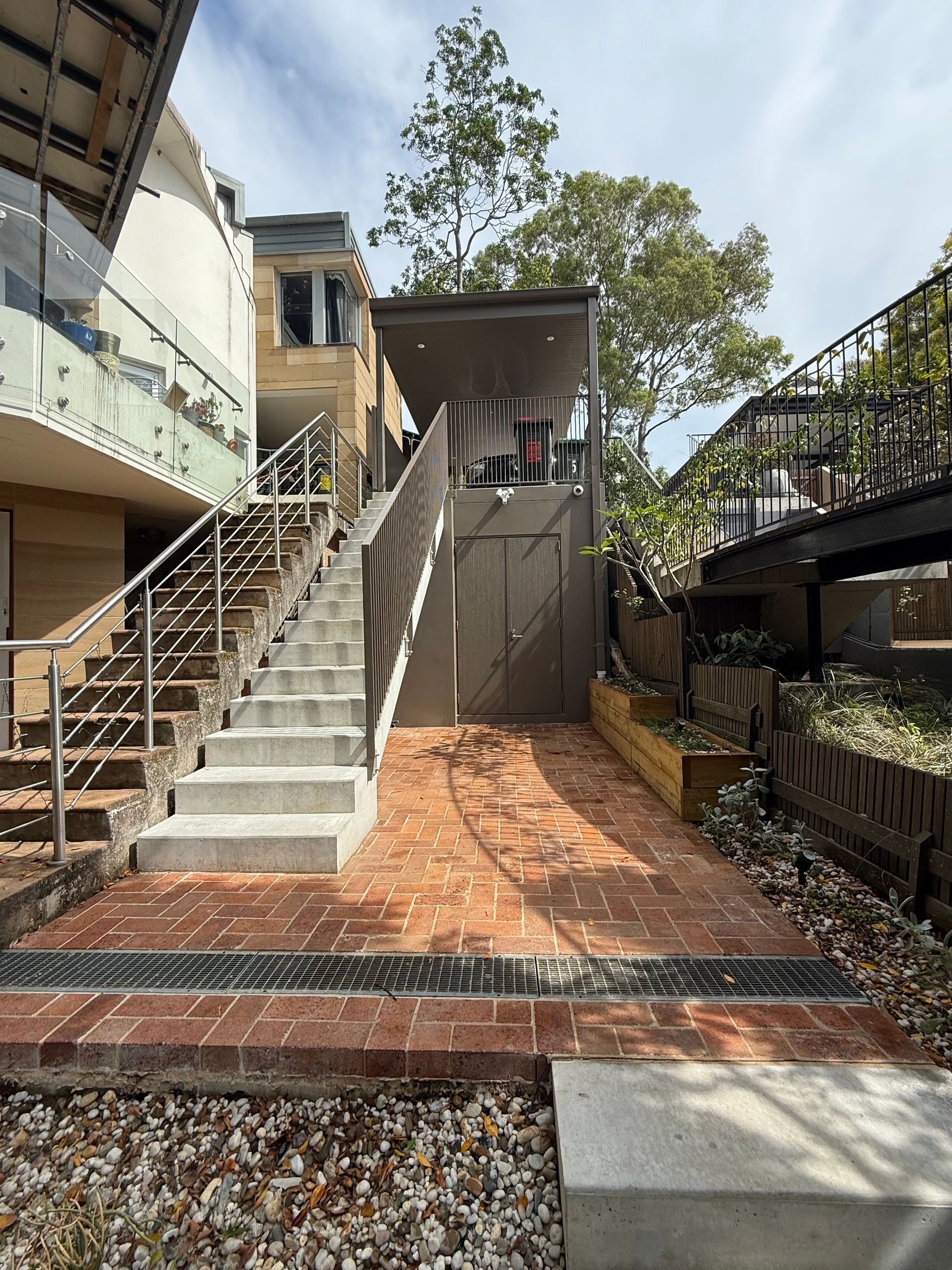 Outdoor stairs leading to a glass-enclosed area with trees in the background.