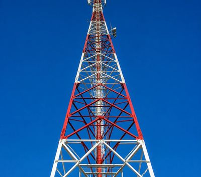 Tall red and white communication tower against a clear blue sky.