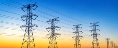 Electricity transmission towers at sunset with colorful sky.