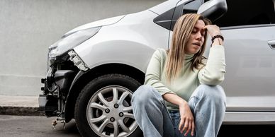 Mujer junto a su carro accidentado, lo que evidencia la importancia de contar con un seguro de autos