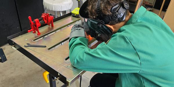 Person welding on a metal table in a workshop.