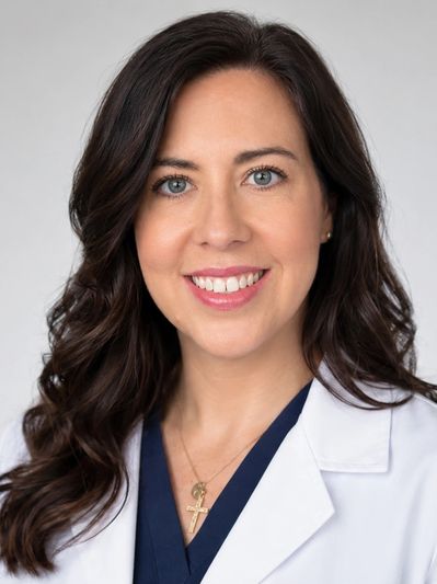 Professional woman with dark hair in a white coat smiling.
