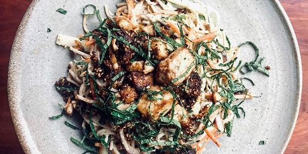 A bowl of tofu salad with shredded vegetables and herbs.