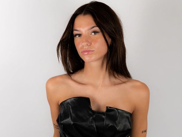 Young woman with dark hair wearing a black strapless top.