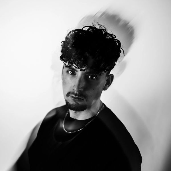Black and white portrait of a man with curly hair and a blurred motion effect.