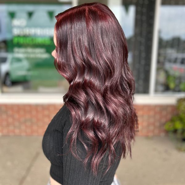 Shiny wavy burgundy hair styled elegantly on a woman.