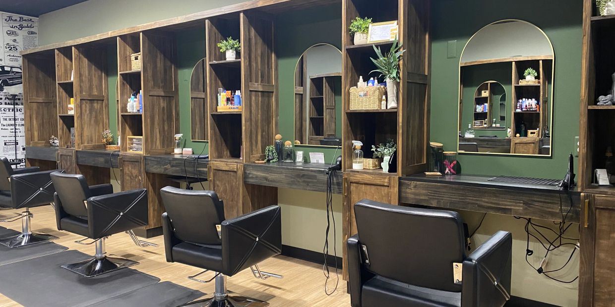 Modern salon with wooden stations and black styling chairs.