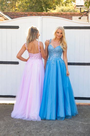 Two women in elegant pink and blue gowns posing outdoors.