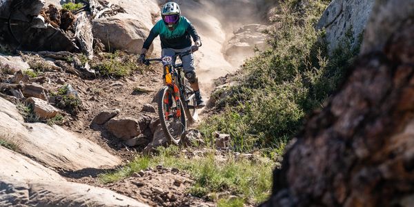 Mountain biker descending a rocky trail in a forest.
