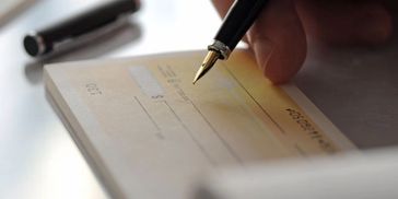 Person writing a check with a fountain pen.