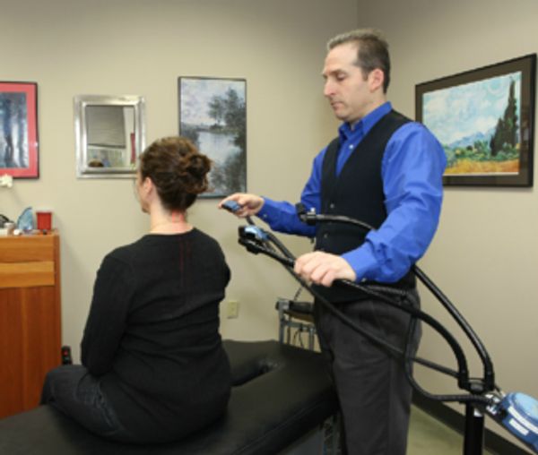 Man treating woman's back with a device in a clinic.