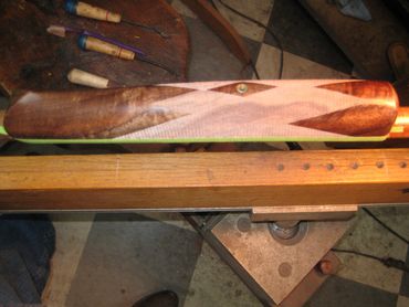Close-up of a wooden gunstock with checkering detail on a workbench.