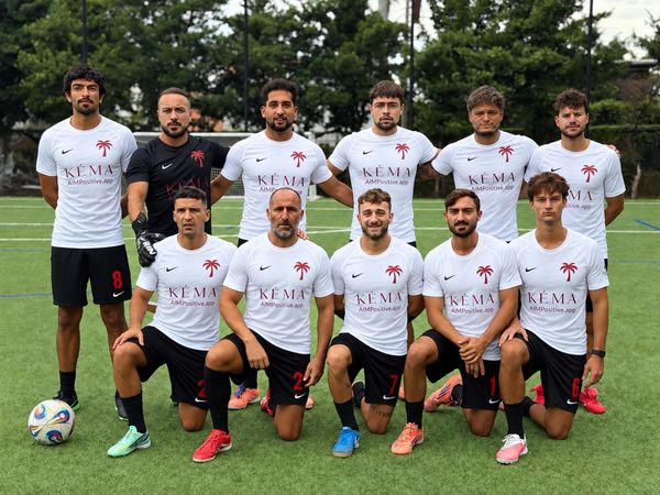 Soccer team posing on a field in white shirts and black shorts.