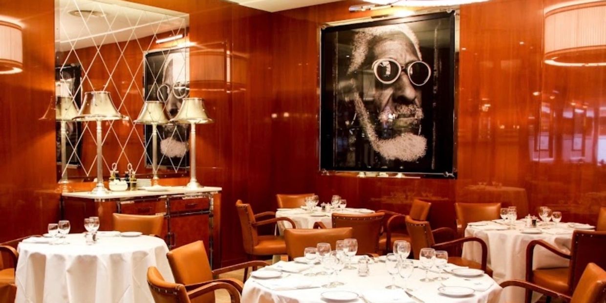 Elegant restaurant with wooden walls and round tables set for dining.