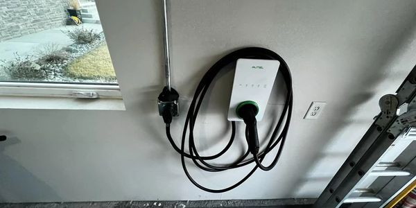Electric vehicle charger mounted on a garage wall with coiled cable.