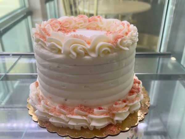White frosted cake with pink sprinkles decoration.