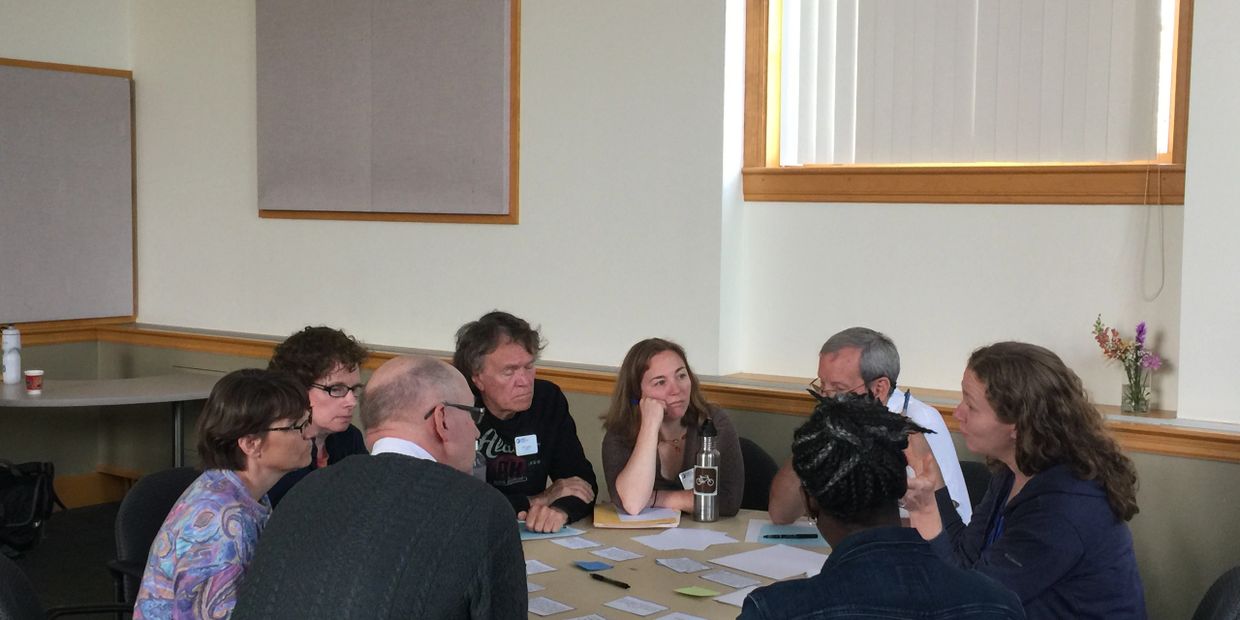 A group of people engaged in a discussion around a table with papers.