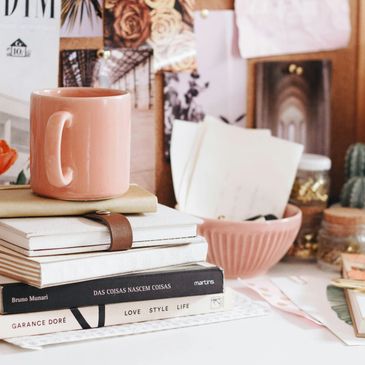 Cozy workspace with stacked books and a pink mug.