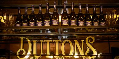 Bottles of prosecco lined up above a sign reading "Duttons".