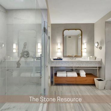 Light stone bathroom with a glass shower, wide vanity, framed mirror, and open shelf of towels.