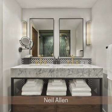 Bathroom with a marble double vanity, gold faucets, two mirrors, and folded towels on an open shelf.