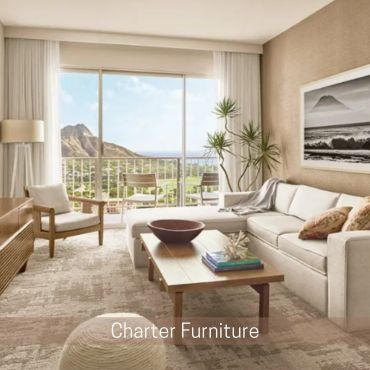 Bright living room with a white sectional sofa, wood coffee table, and balcony overlooking a mountai