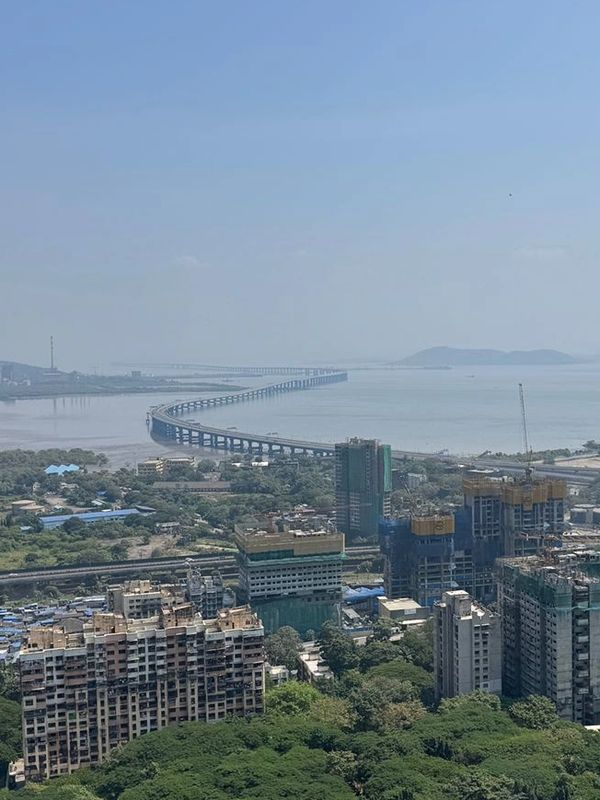 Curved bridge extending over water with cityscape in foreground.