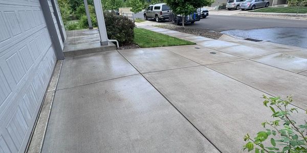 Clean concrete driveway and sidewalk in a residential neighborhood on a rainy day.
