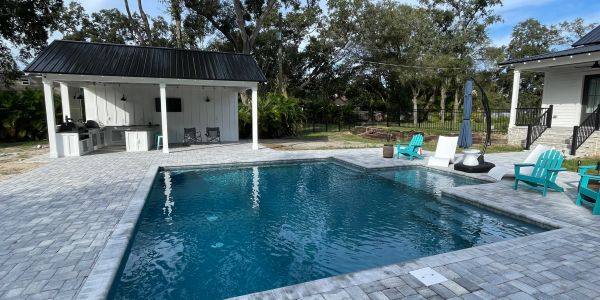 Brine designed and constructed modern backyard pool with seating and covered outdoor custom kitchen area.