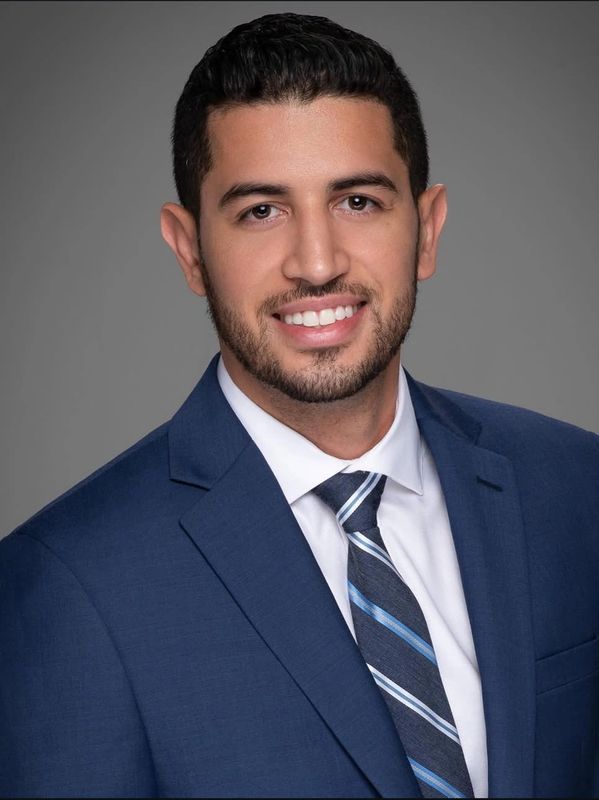 Professional young man in a blue suit smiling confidently.