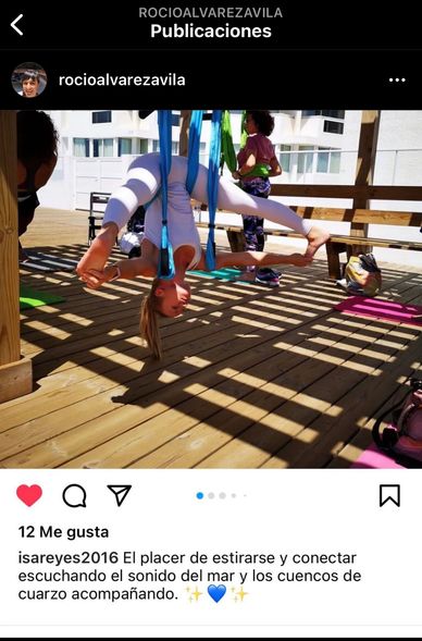 Persona estirándose con ayuda de cuerdas en un espacio al aire libre.