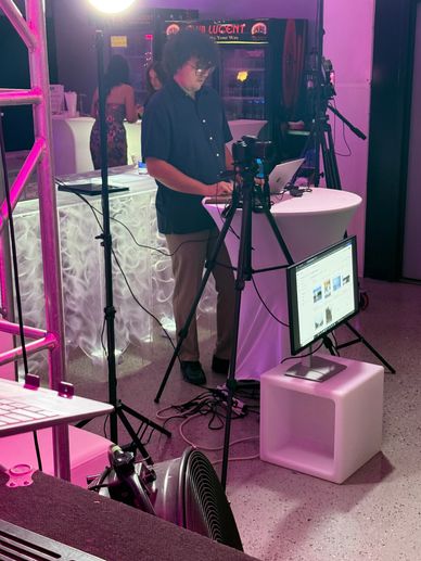 Man working with camera and computer at event setup.