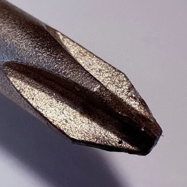 Extreme close-up of a worn-out Phillips screwdriver tip.