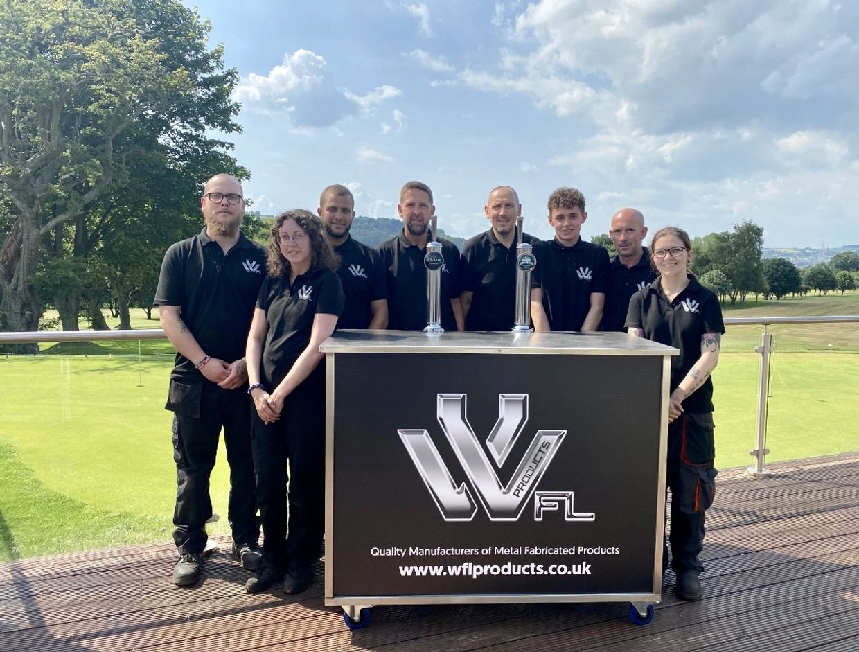 Team photo of eight people wearing black WFL Products shirts outdoors.