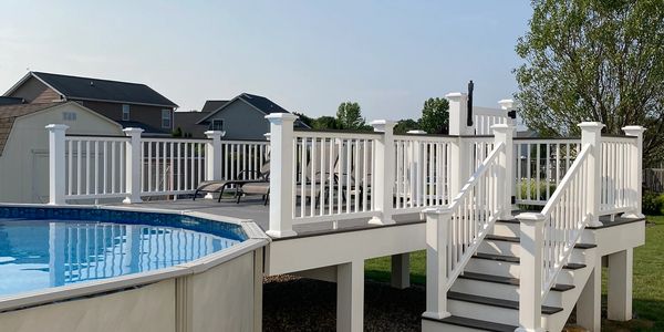 A white deck with stairs leading to an above-ground swimming pool.