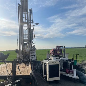 Industrial machinery setup on a trailer in a rural field under a blue sky.