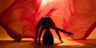 Silhouette of a dancer with flowing red fabric.