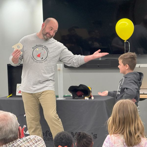 Man performing science demonstration for children.