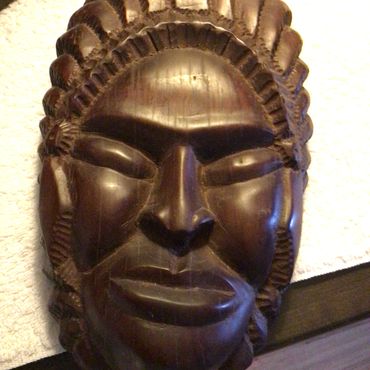 Dark wooden carved tribal mask with intricate details.