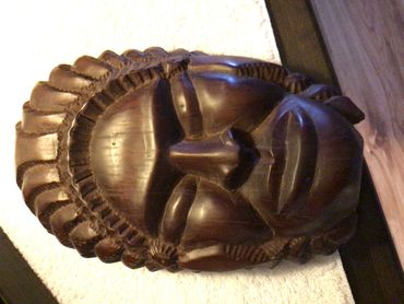 Dark wooden carved tribal mask with intricate details.