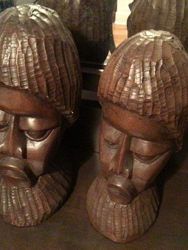 Two wooden carved busts with textured hair and beards.
