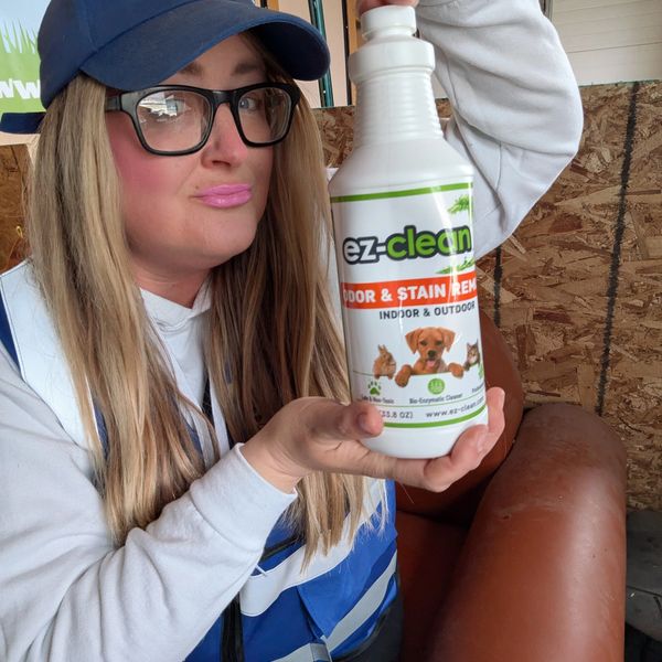 Woman holding a bottle of ez-clean odor and stain remover.