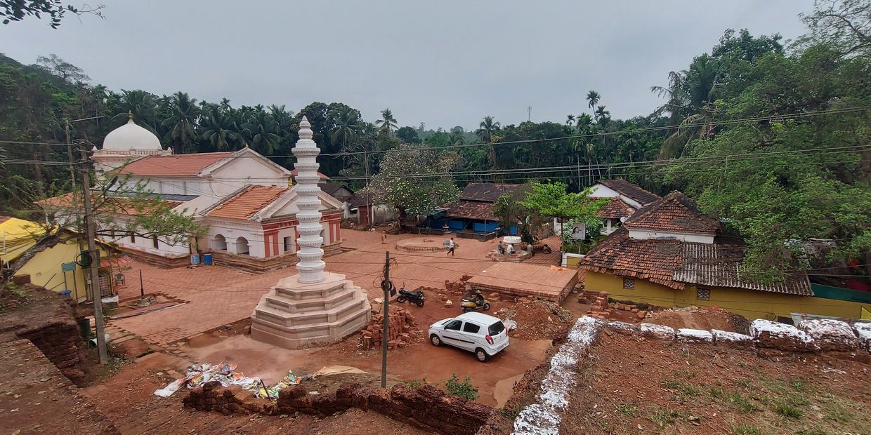 View of a temple courtyard with a white pillar and several buildings around.