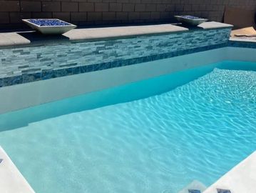 Clear blue water in a backyard pool under sunlight.