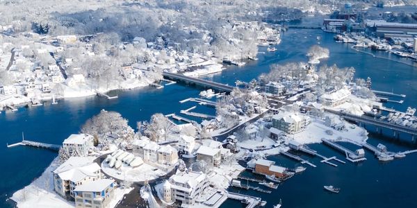 A snowy coastal town with docks and boats on a clear winter day.