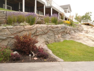Concrete retaining wall formed to blend in with natural bedrock in yard.